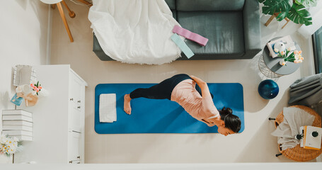 Top view of Young sporty Asia strong woman in sportswear with calm feeling warming up stretching practice yoga for beginner in living room at house. Home quarantine workout and fitness exercise.