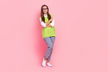 Fototapeta na wymiar Full length photo of cheerful girl straight hairstyle dressed green vest look directing empty space isolated on pink color background