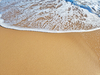 Ocean foam covering beautiful sandy beach. Closeup.