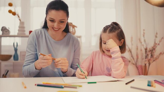 Mother and little daughter drawing together at home, indoor activities