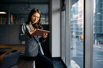 Asian businesswoman working on digital tablet in office.