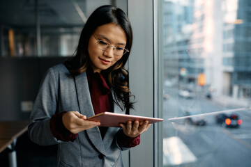 Asian female executive using digital tablet by window.