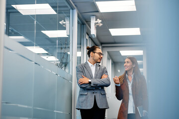 Happy business colleagues talk wile walking through hallway in office.