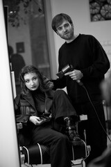 man hairdresser dries female hair with hairdryer after washing