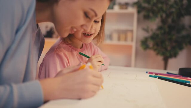 Positive mother and her daughter drawing together, happy childhood, family