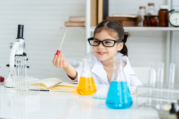 Adorable  Arab girl believes that it's cute to sit in a science class. science practice Squeeze the water from the bottle into the beaker, slowly mixing the colors together. and see the difference