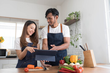 Romantic couple is cooking on kitchen. Handsome man and attractive young woman are having fun together while making salad. Healthy lifestyle concept.