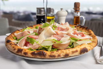 Classic Italian pizza with arugula and prosciutto, Mediterranean pizza with served table