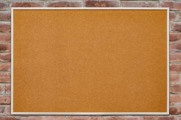 Fototapeta premium An empty cork board is hanging on a brick wall. Copy space.