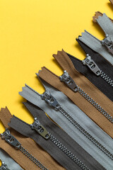 Set of zippers on a yellow background. Sewing tools. Top view. Copy space.