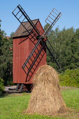 Old red wooden windmill with a haystack in the foreground. Finnish agriculture.