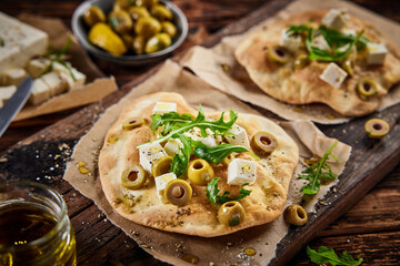 Delicious pita with cheese olives and seasonings served on wooden table
