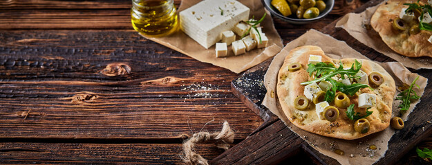 Fototapeta na wymiar Delicious homemade flatbread with cheese olives and herbs on table