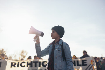 Teenage girl with megaphone in hand in the middle of a demonstration
