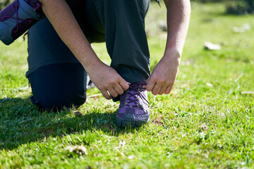 Fototapeta na wymiar Close up view of a person tying shoelaces outdoors in nature.