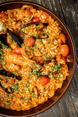 plate of risotto alla pescadora with seafood, on a rustic wooden background
