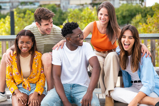 Group of five cheerful multiracial friends having fun outdoors - happy young people laughing together at city - Friendship concept.
