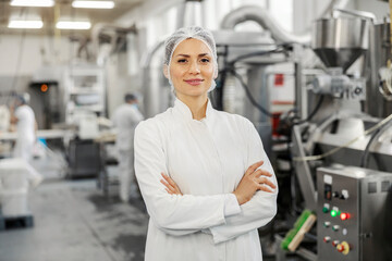 Portrait of a successful food factory manager in sterile uniform with arms crossed smiling at the...