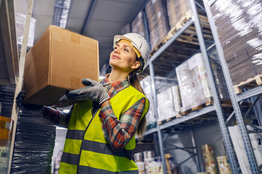 A warehouse worker is arranging box on shelf and preparing it for delivery.
