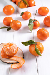 Fresh clementines with leaves on white wooden table..