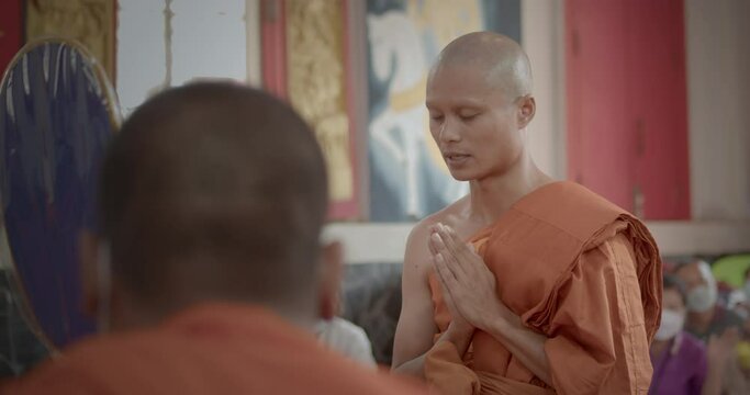 A slow-motion scene of a man who must be over twenty years old dressed in monk robes put his hands together to the preceptor and monks to ask for ordination as a Buddhist monk.