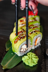 Sushi roll with smoked eel unagi covered by avocado and sesame seeds