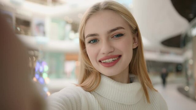 Webcam view blogger Caucasian woman lady shopper blonde girl record blog in shopping mall online video streaming for social media looking at mobile phone selfie camera speaking talking trend blogging