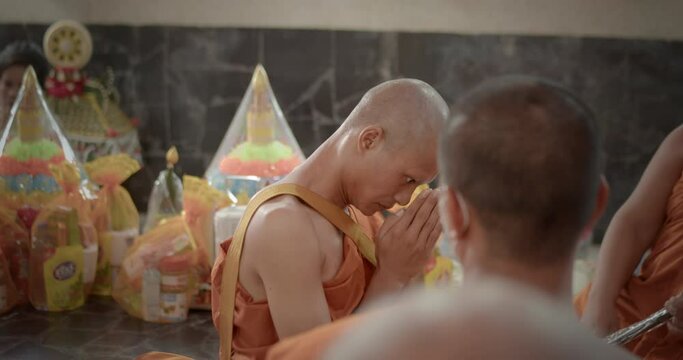 A slow-motion scene of a man who must be over twenty years old dressed in monk robes put his hands together to the preceptor and monks to ask for ordination as a Buddhist monk.
