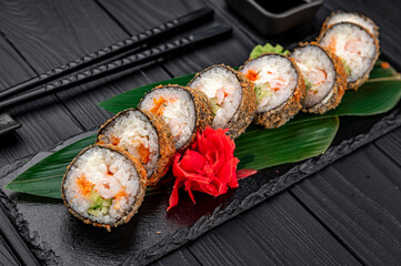Hot tempura roll with salmon and cheese, Traditional delicious fresh sushi roll set on a black background.