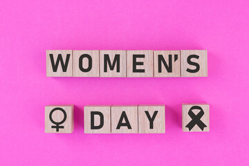 International Women's Day written on wood on a pink background.