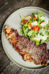 Cut of meat with fresh salad on a rustic wooden board
