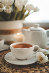 Cup with tea close-up, tulips and a candle, atmospheric photo