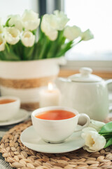 Fototapeta na wymiar Cup with tea close-up, tulips and a candle, atmospheric photo