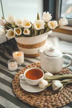 A cup of tea against the background of a basket with tulips in a cozy interior, spring still life