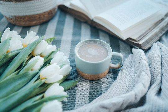 A cup of cappuccino, a bouquet of tulips, an open book and a gift, good morning aesthetics