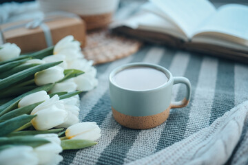 A cup of cappuccino, a bouquet of tulips, an open book and a gift, good morning aesthetics
