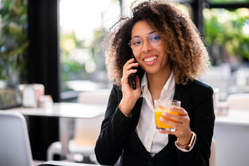 Young afro american businesswoman on the phone with an orange juice