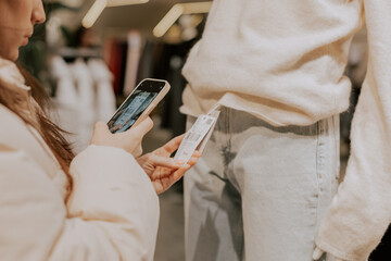 The girl scans the price tag on a mobile phone in the store.