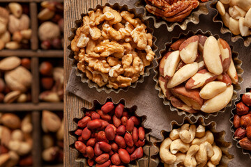 Varied kinds of peeled nuts in the metal bowls in rustic style
