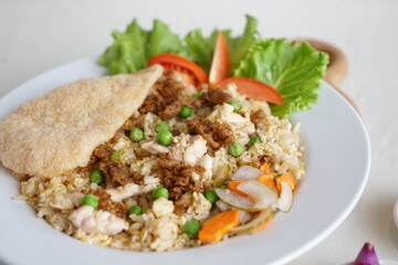 Chinese fried rice with kerupuk served in a white plate. on a white background