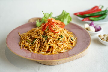 mie tek tek or  javanese fried noodle made with egg noodles with chicken, cabbage, meatballs, scrambled eggs. indonesian food