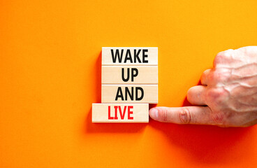 Wake up and live symbol. Concept words Wake up and live on wooden blocks. Beautiful orange table...