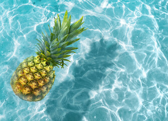 Yellow pineapple on a blue water background. Tropic concept.
