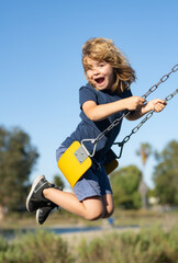 Swinging on playground. Child boy on swing. Kid swinging on playground. Cute excited amazed child...