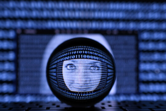 Concept for AI artificial intelligence or operating system or identity theft online. A female face in the midst of binary data stream on a computer screen as seen through a lens ball.