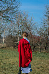 A girl in a red coat stands in nature.A woman walks.Pose in motion.Vintage retro photo.Beautiful image.A woman takes off her coat.Walks on green grass.Cold season.Lonely girl.
The emotion.Loneliness.