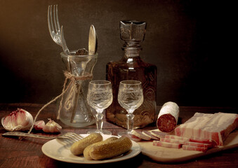 Stylized still life with a bottle of vodka or moonshine with a glass, bacon, sausage and cucumber. - 571684795