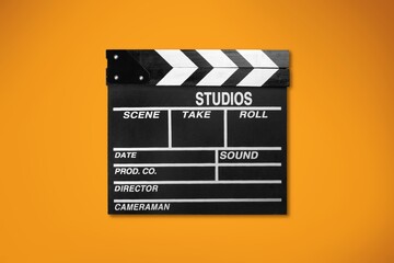 Naklejka premium Classic movie clapperboard on colored desk