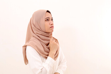 Side view of young asian muslim woman thinking something while looking above on blank space