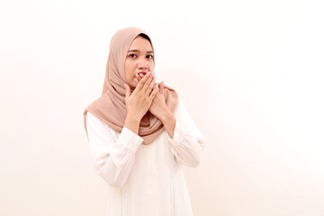 Shocked young asian muslim woman looking on camera and covering mouth. Isolated on white background